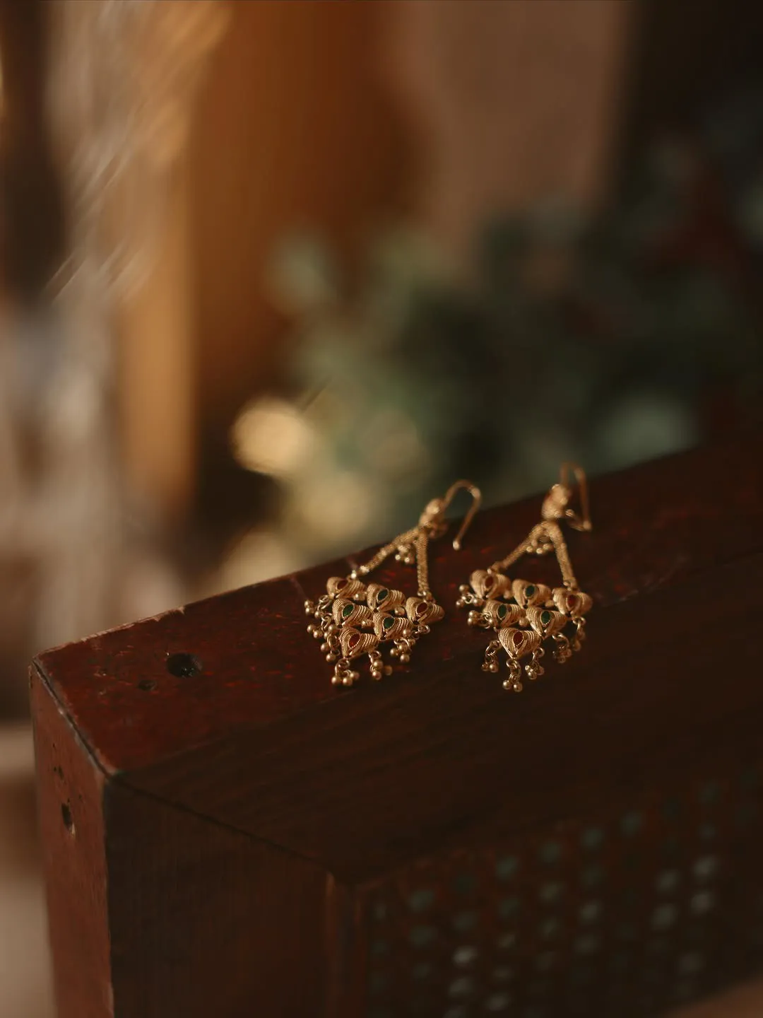 Gold chandelier earrings resting on a carved wooden box
