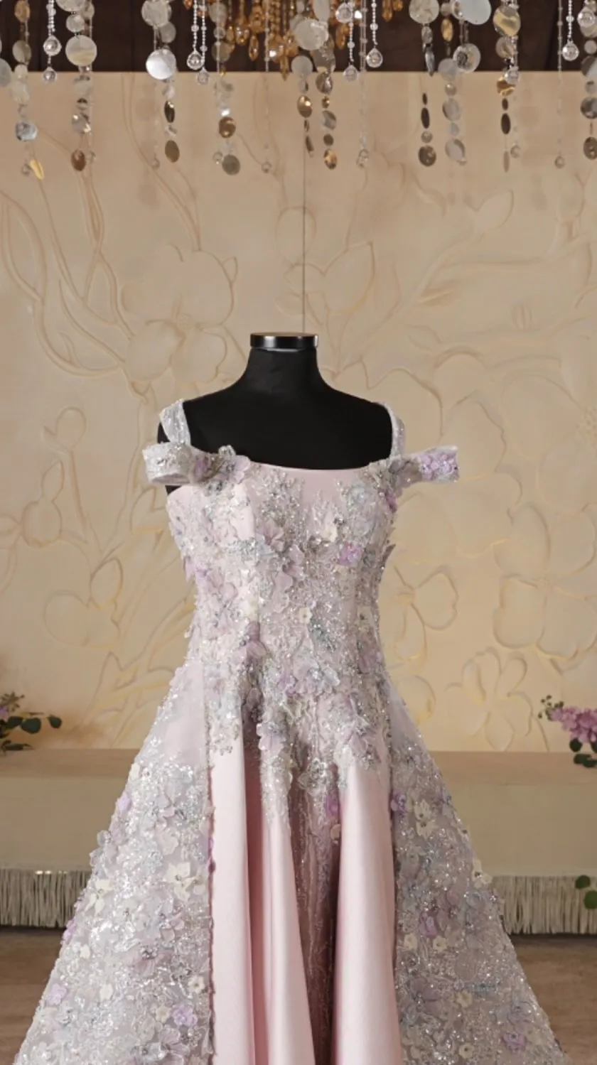 A blush pink gown with lilac floral embroidery under hanging crystals