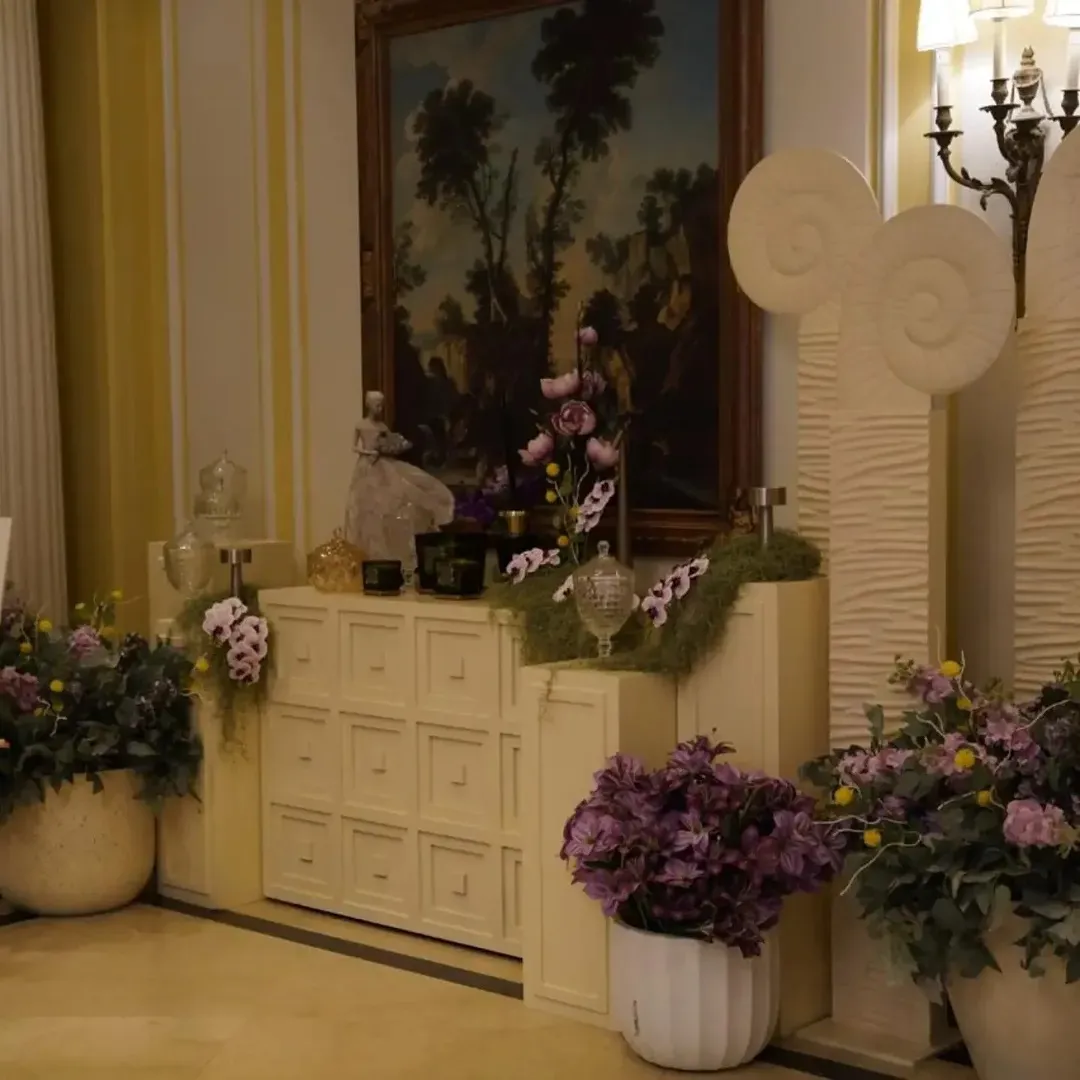 An off-white console with lavender orchids and sculpted panels