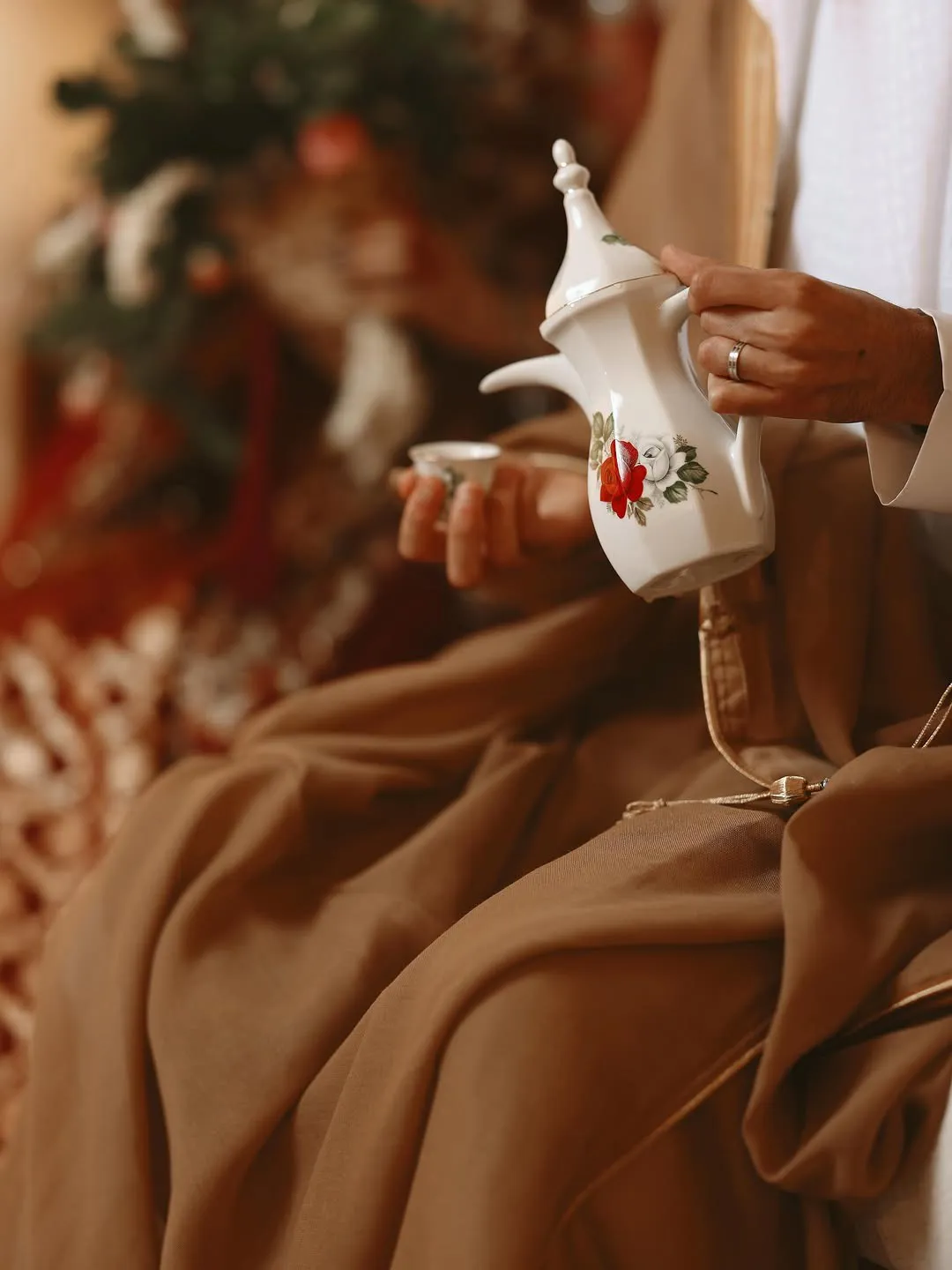 Arabic coffee poured from a white dallah painted with red and white roses